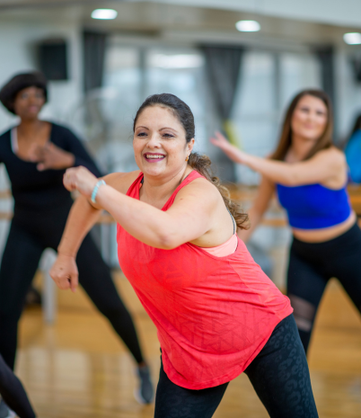 Several women participate in a Zumba class. They are smiling and having fun.